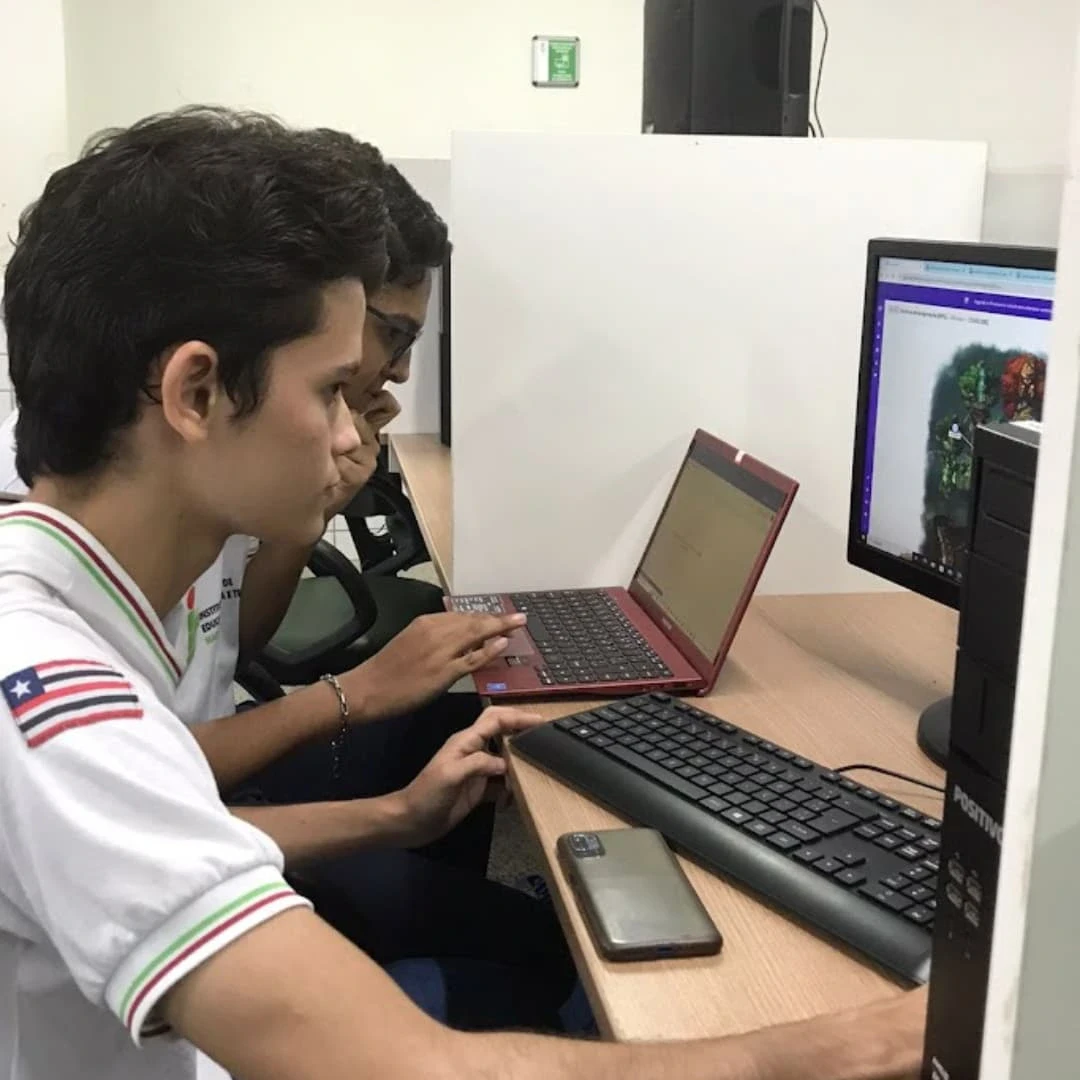 Estudantes trabalham em computadores no laboratório