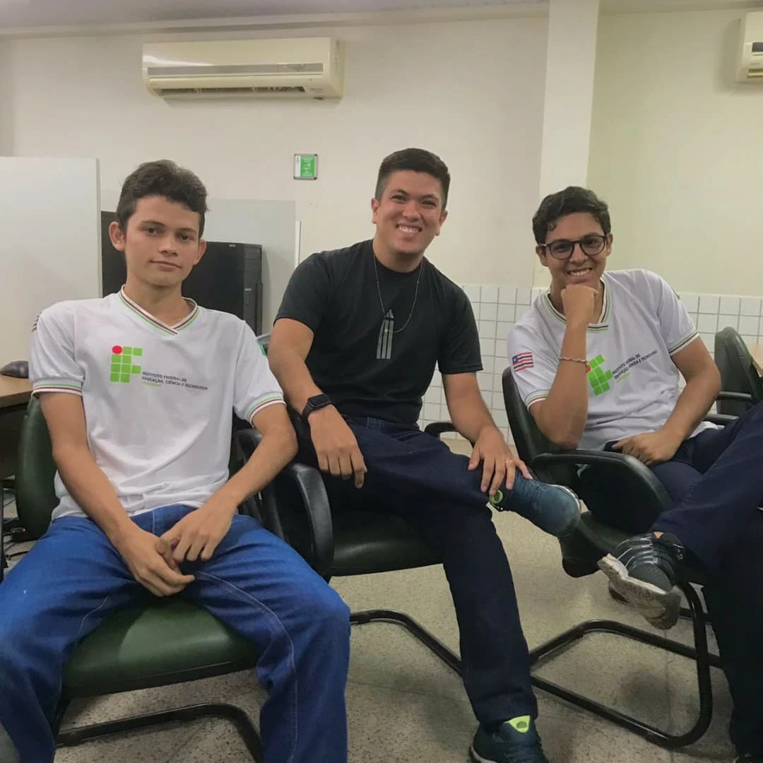 Três estudantes sentados em uma sala do laboratório