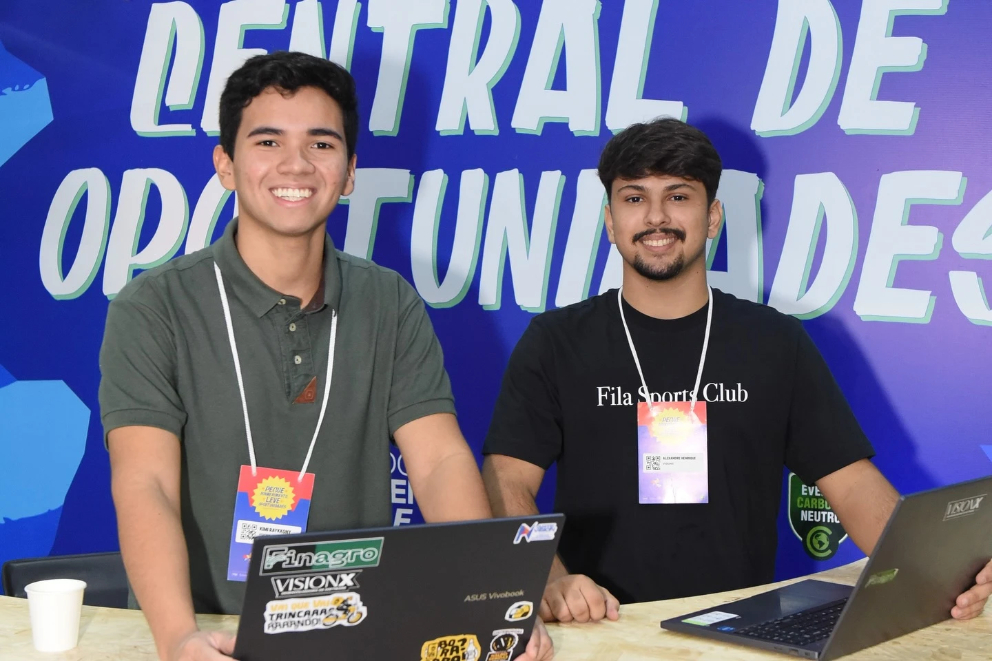 Dois integrantes da equipe no balcão da Central de Oportunidades, com notebooks com adesivos da VisionX e do Finagro