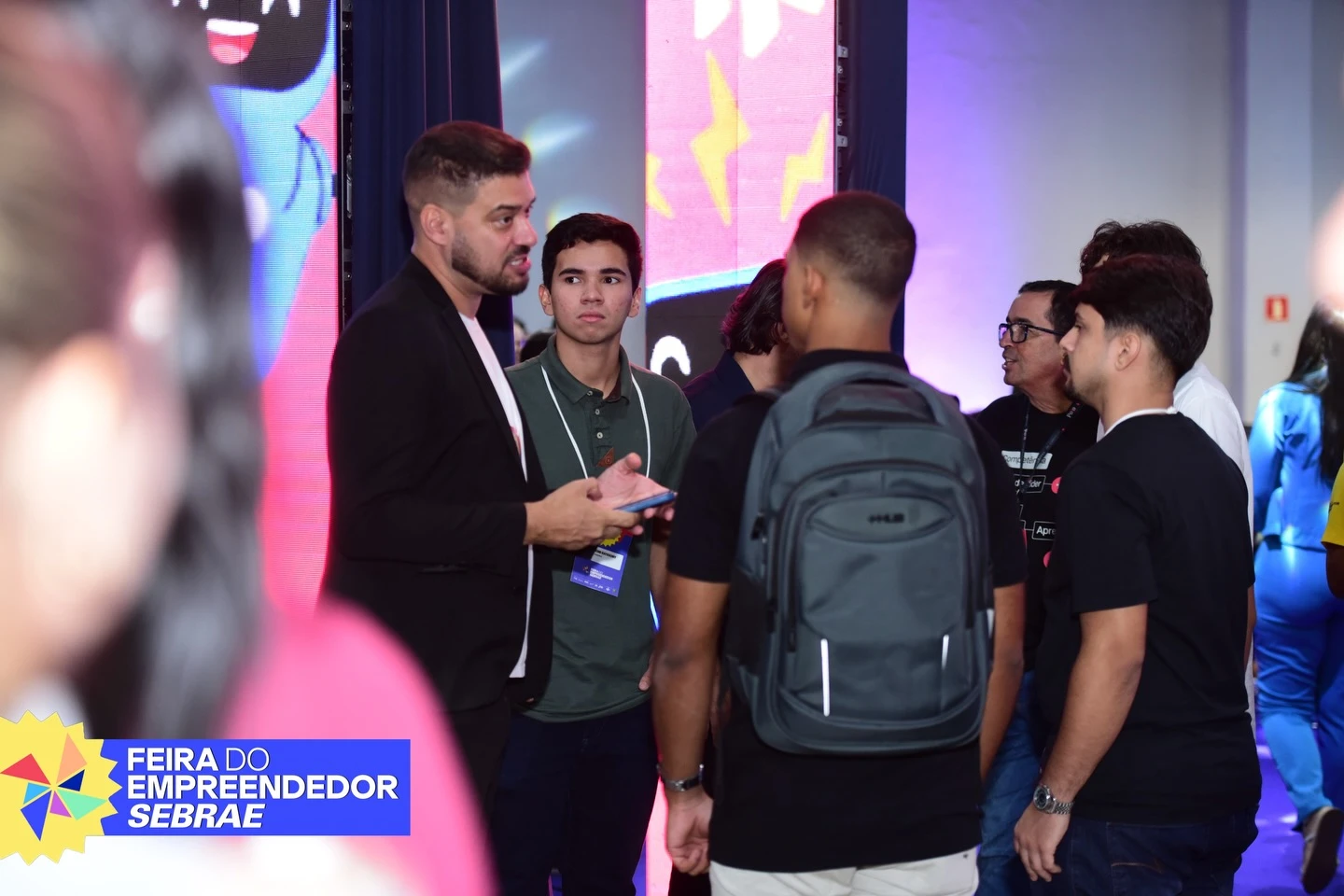 Participantes e integrantes da equipe conversam em um corredor do evento