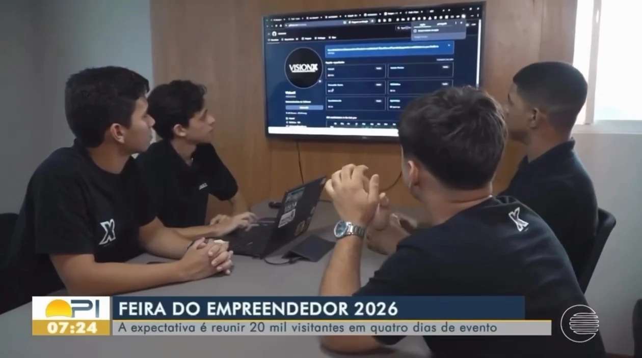 Quadro da reportagem de TV: equipe da VisionX reunida diante de uma tela, com a chamada Feira do Empreendedor 2026